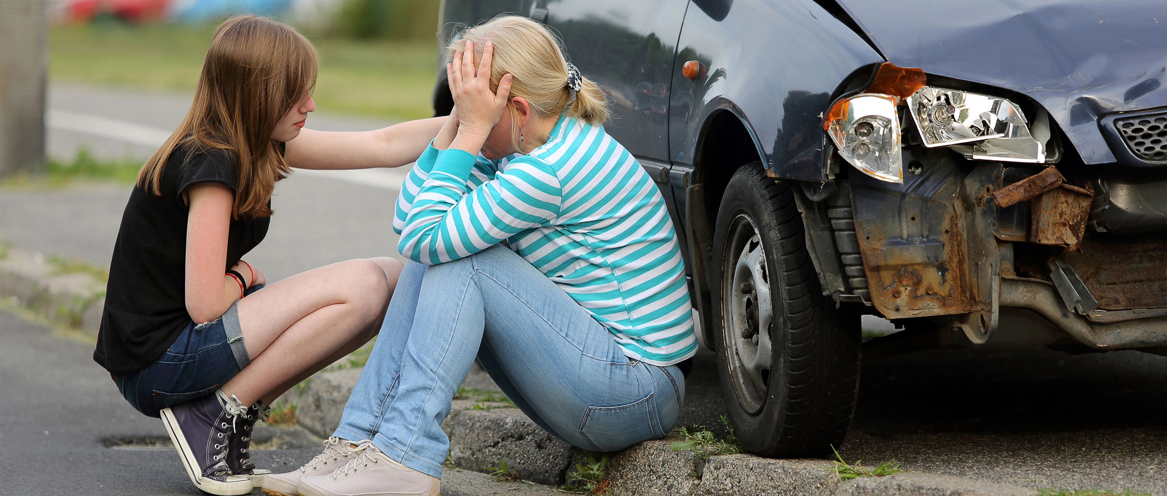 femmes assises au bord d'un trottoir après un accident de voiture