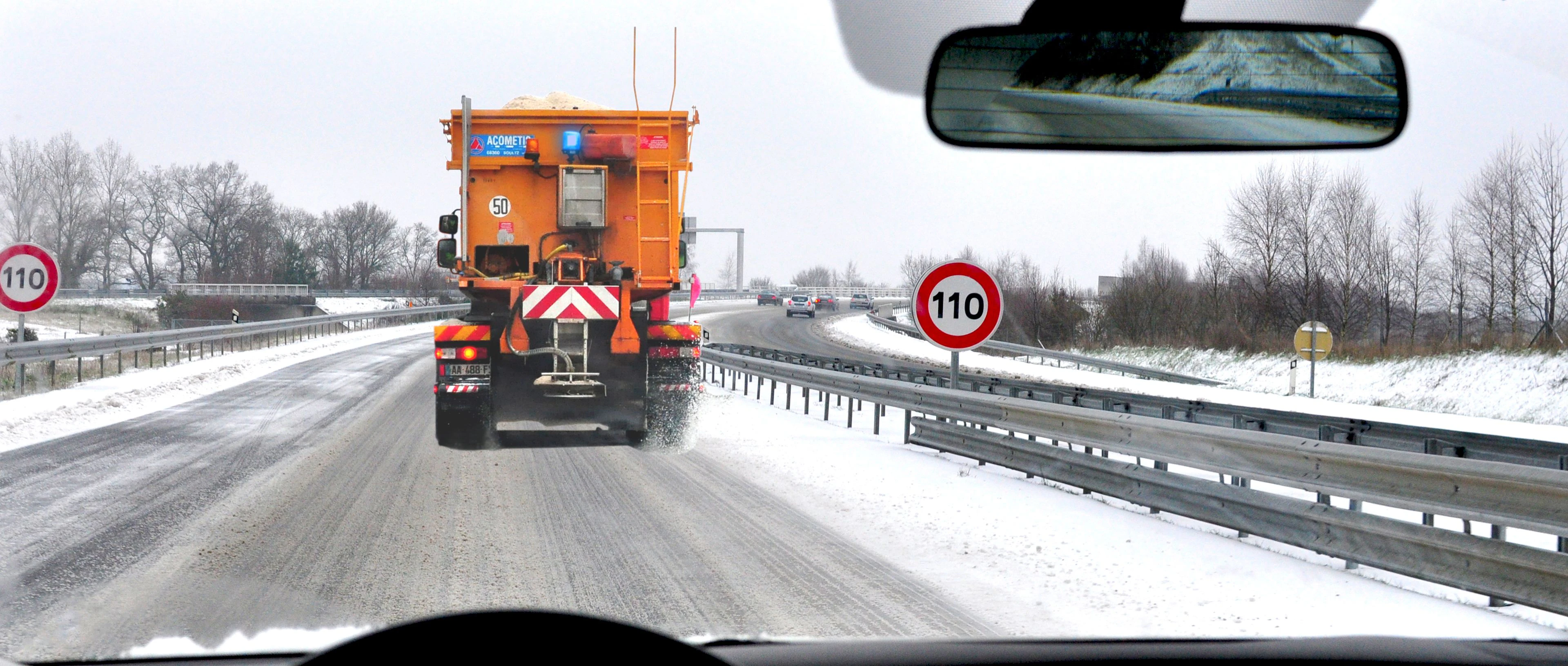véhicule lent qui circule sur une route enneigée 