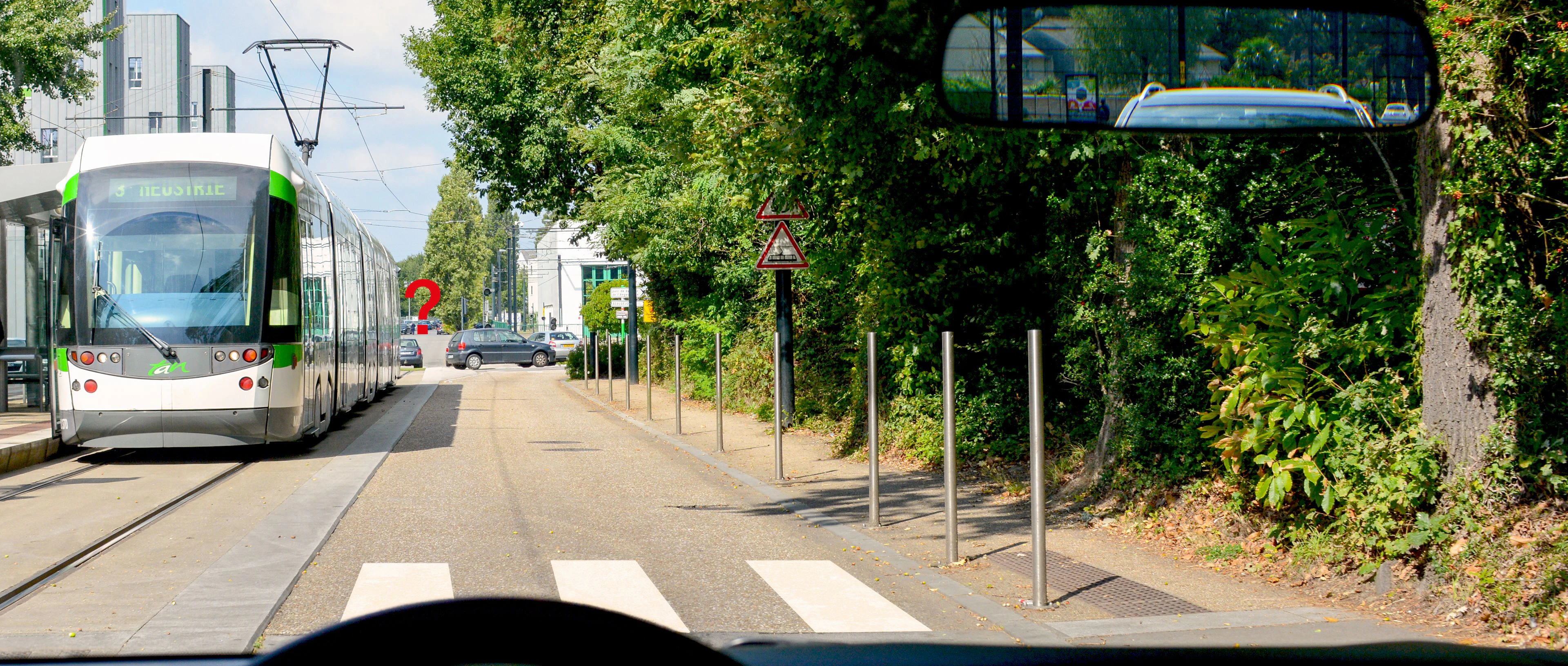 voiture qui circule à côté d'un tramway