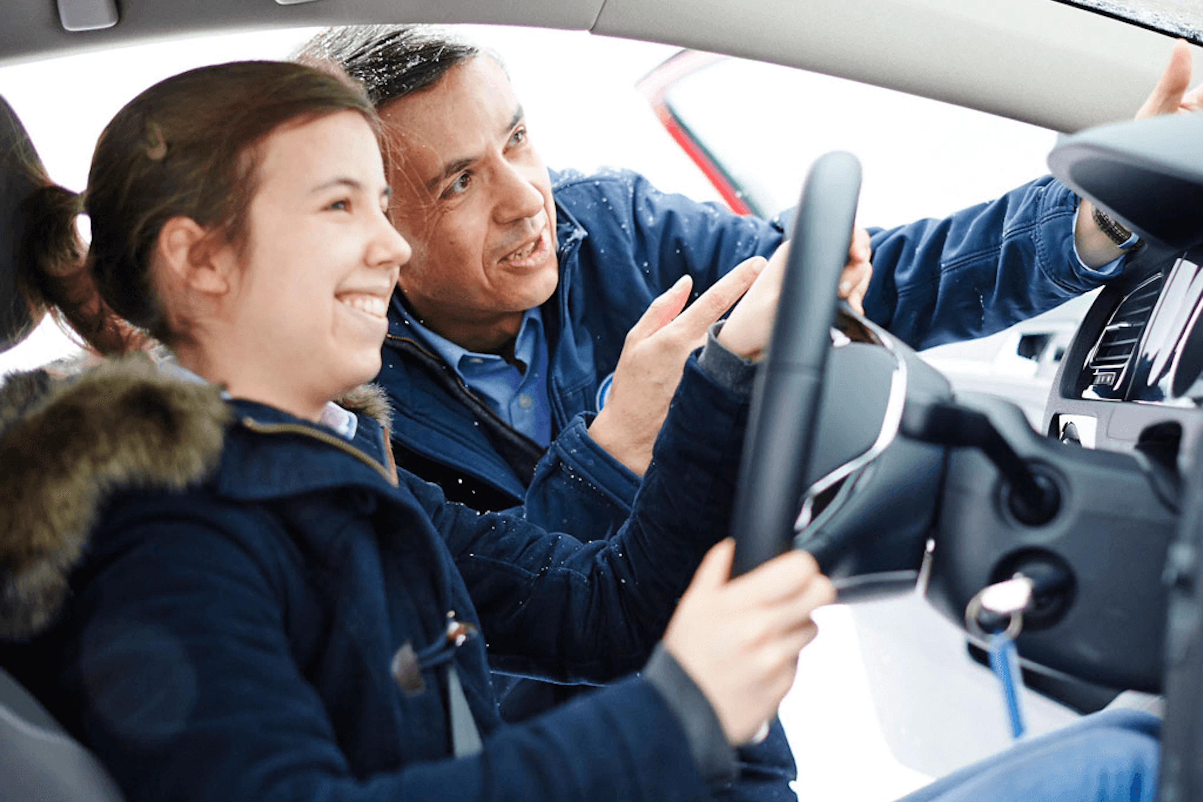 Élève au volant d'une voiture avec son moniteur debout à côté