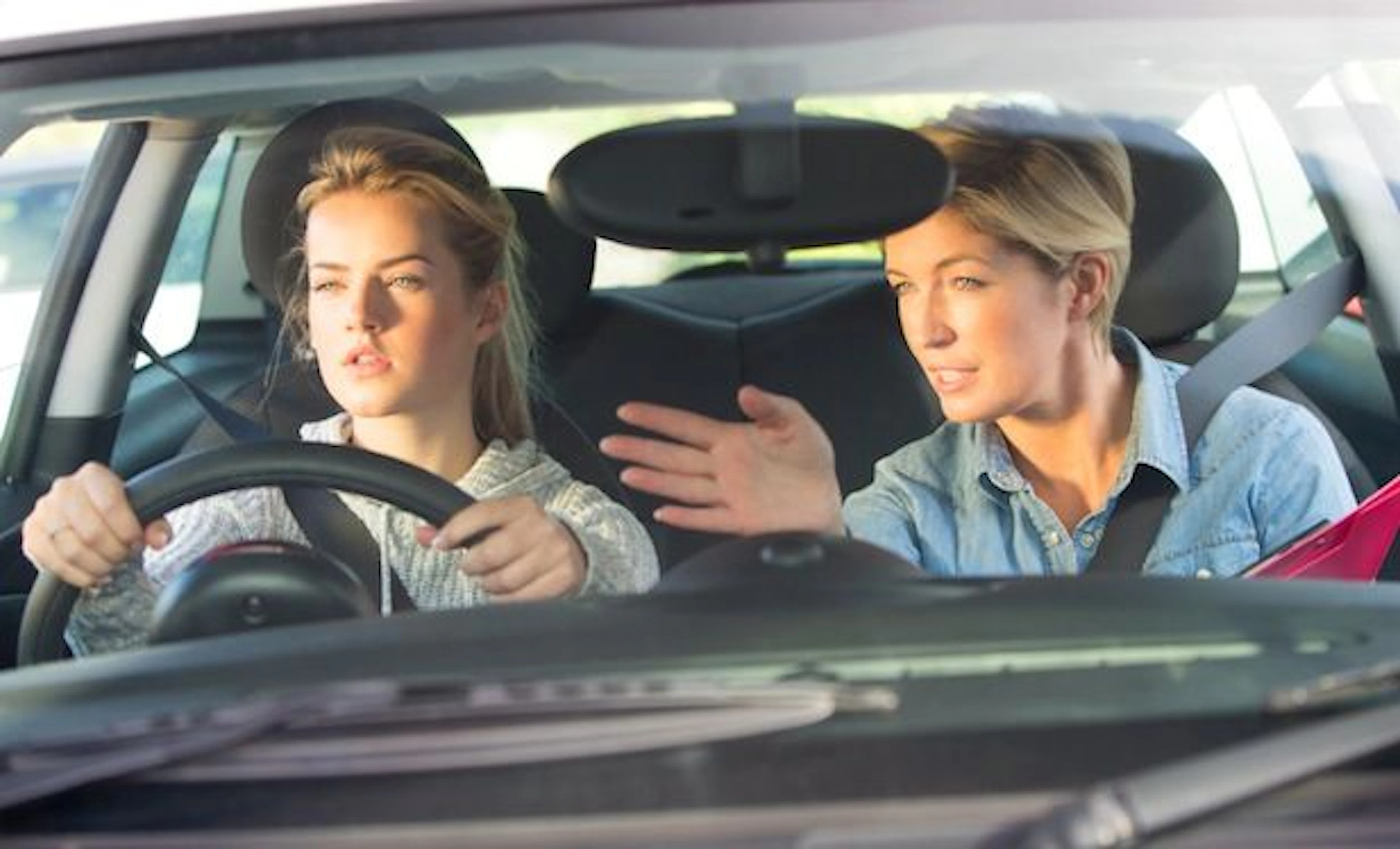 Élève au volant d'une voiture avec sa monitrice