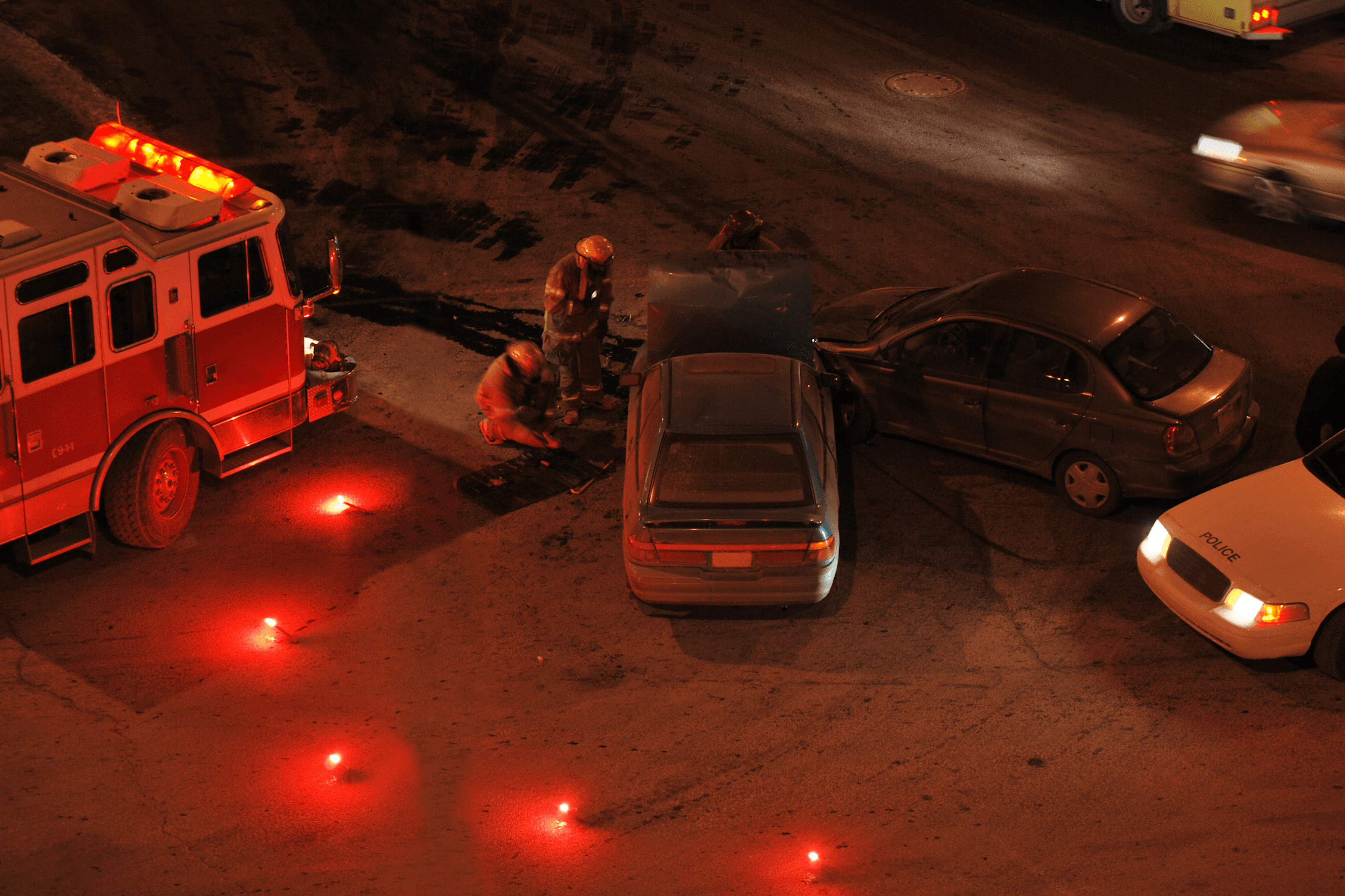 Accident de deux voitures - pendant la nuit - on peut voir une voiture de police et des pompiers