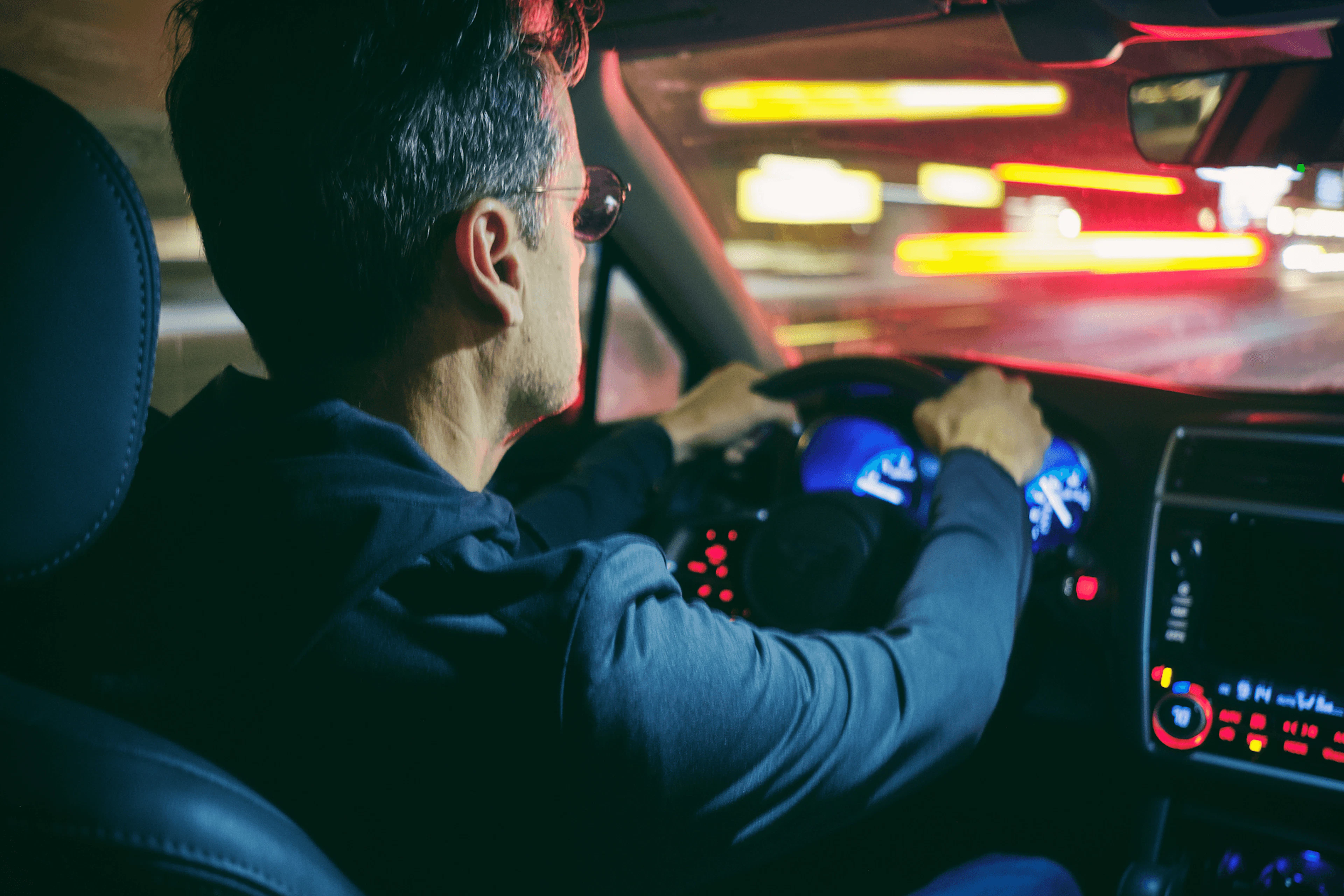 Un homme au volant d'une voiture sur une route sur pendant la nuit
