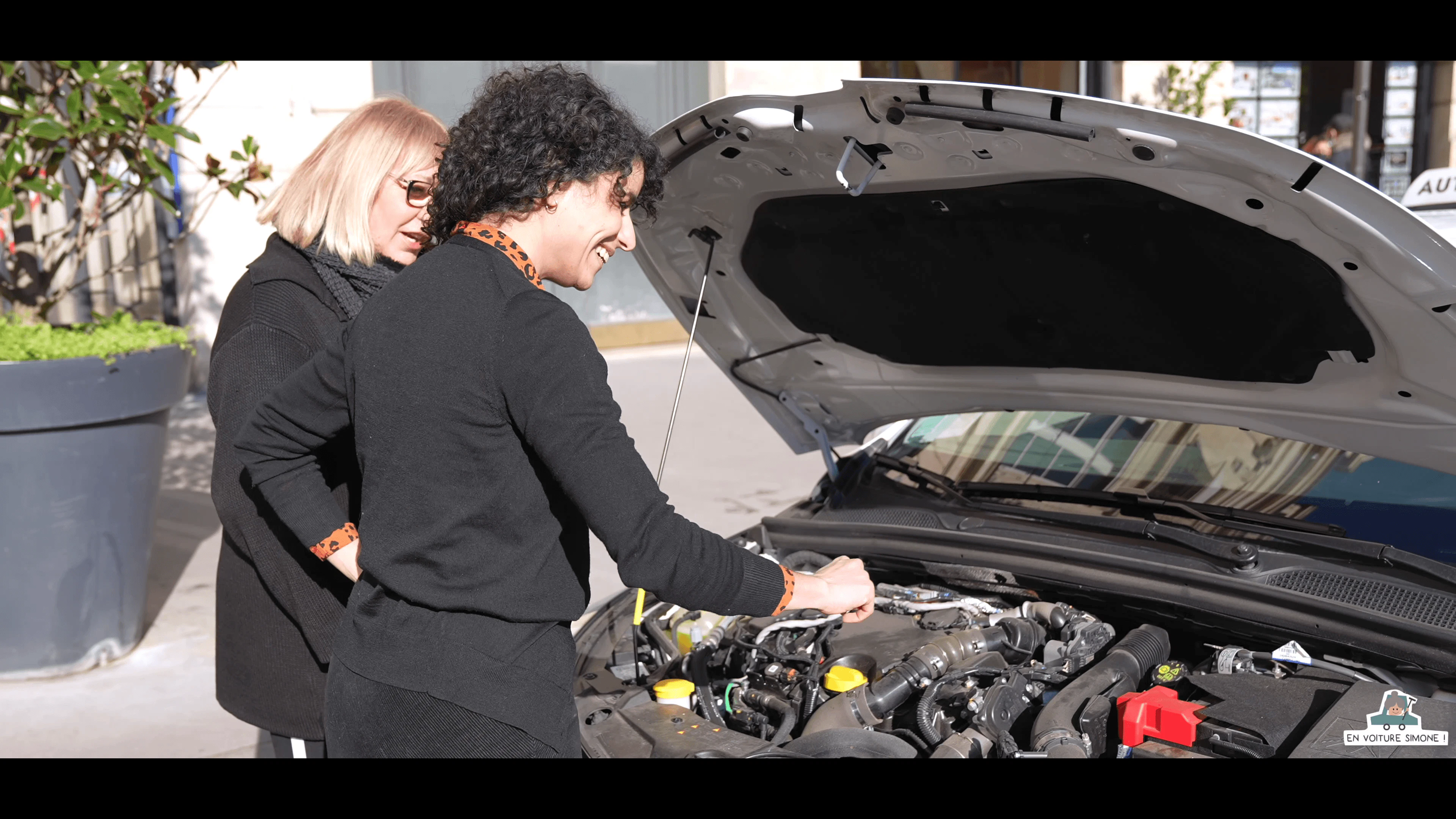 Élève et sa monitrice regardent les éléments sous le capot d'une voiture