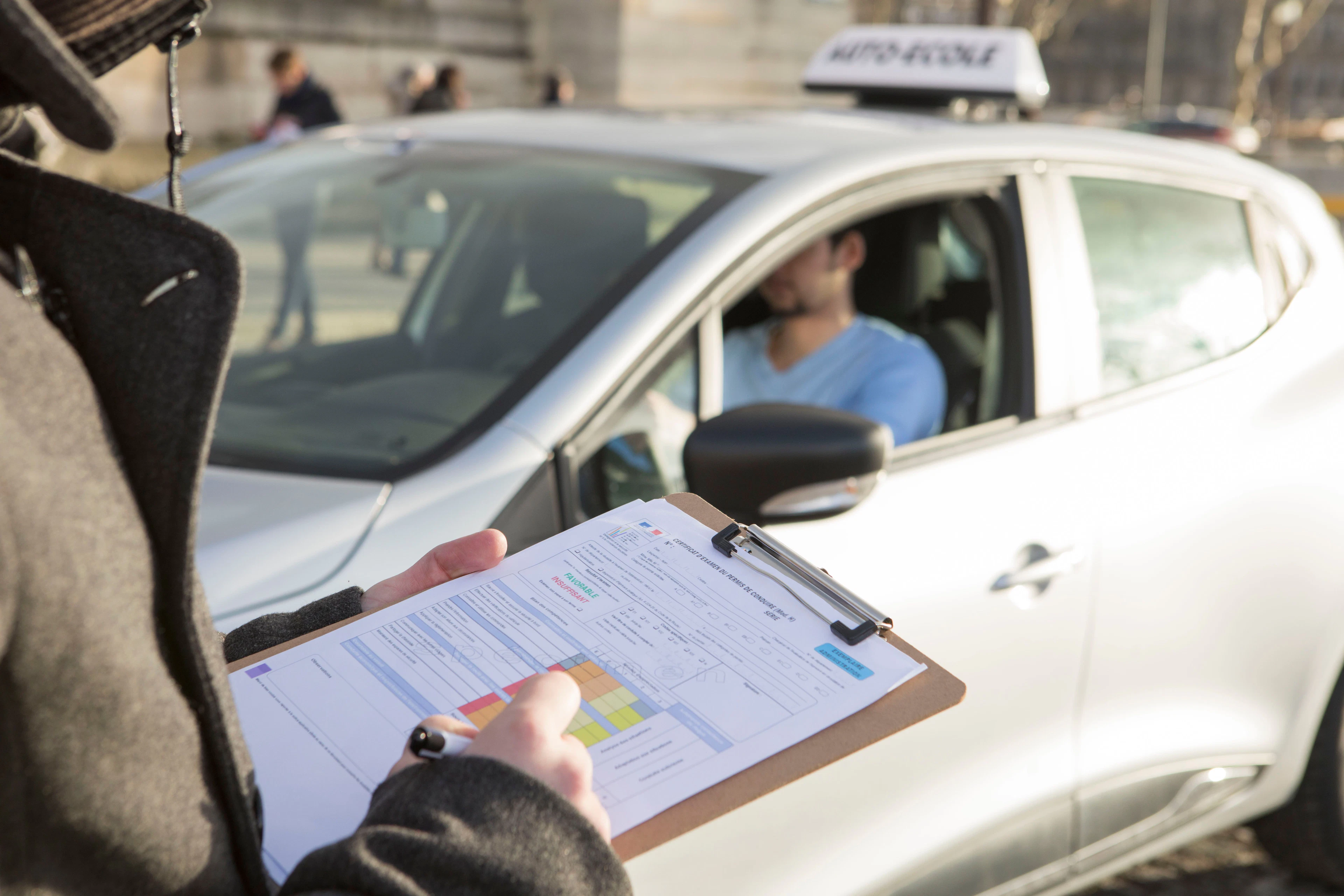 Examinateur du permis de conduire remplissant la grille d'évaluation